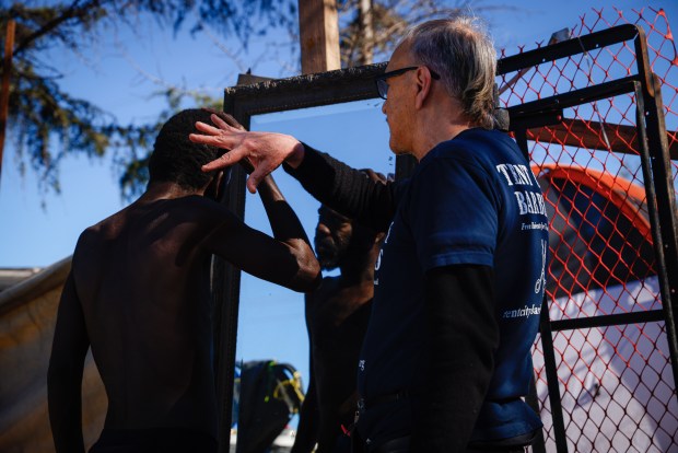 Joseph Kautz habla con Garnett Pittman sobre cómo decidió cortarse el pelo en un campamento en Redwood City, California, el sábado 10 de febrero de 2024. Pittman fue un niño adoptivo y comenzó a vivir en las calles detrás de su madre adoptiva.  muerte.  (Shae Hammond/Grupo de Noticias del Área de la Bahía)