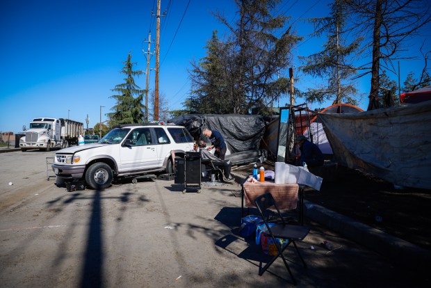 Joseph Kautz le corta el cabello a Garnett Pittman en un campamento en Redwood City, California, el sábado 10 de febrero de 2024. Pittman era un antiguo niño adoptivo y comenzó a vivir en las calles después de la muerte de su madre adoptiva.  (Shae Hammond/Grupo de Noticias del Área de la Bahía)