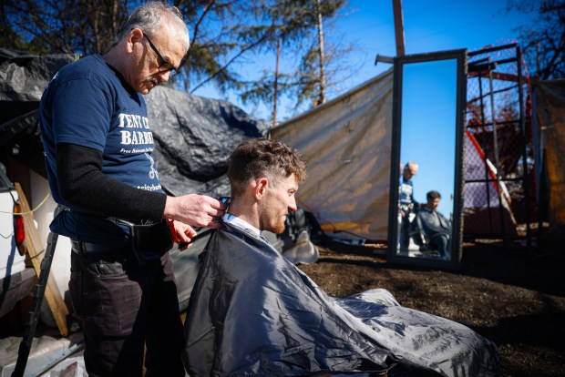 Scott Llewellyn, que vive en un campamento en Redwood City, es cortado por Joseph Kautz en el campamento en Redwood City, California, el sábado 10 de febrero de 2024. (Shae Hammond/Bay Area Newsgroup)