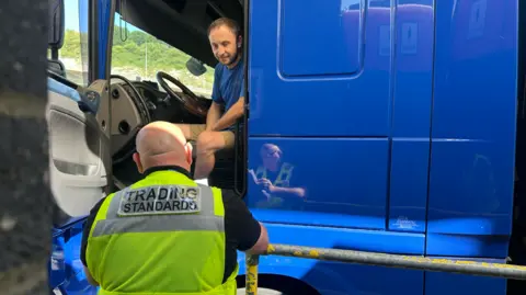BBC / Josie Hannett es un gerente estándar que ve el pasaporte y el conductor del conductor, que es su puerta viviendo en un grupo de tarjeta azul