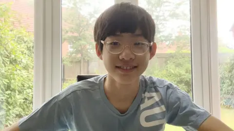 Nacios de niños con cabello negro corto, gafas y abrigos azules, mientras estaba en la hospitalidad. El jardín también puede estar jardinando la ventana después de él.
