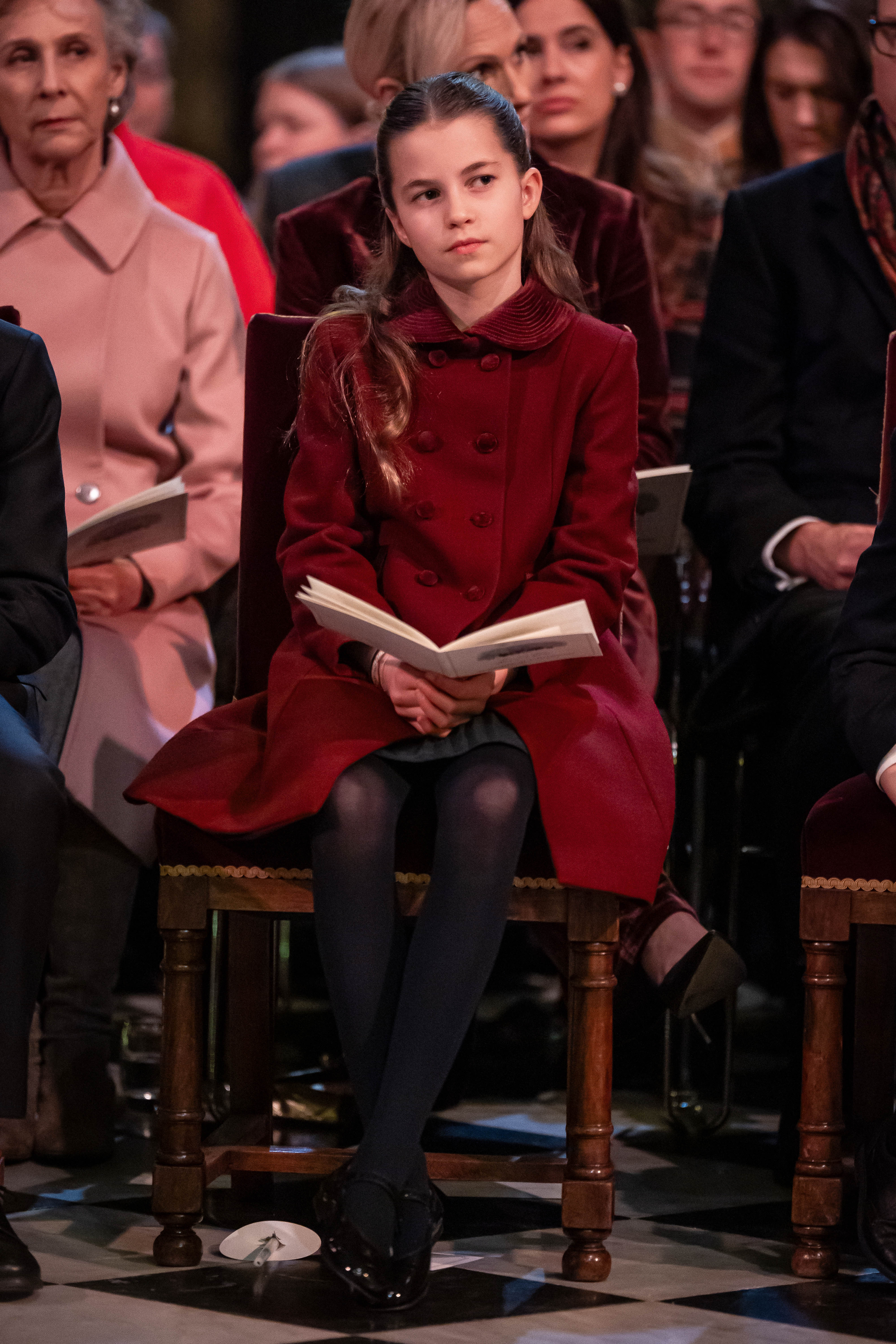 La princesa Charlotte viste un abrigo color burdeos mientras está sentada en la capilla dentro de la iglesia.