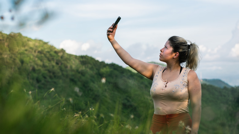 Una mujer sosteniendo un teléfono en el cielo.