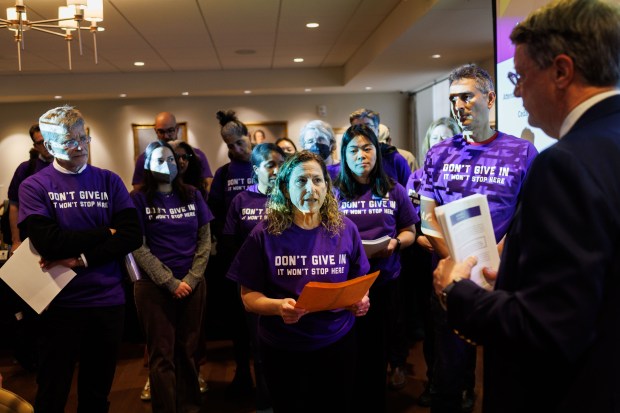 Julie Biehl, profesora clínica de derecho en la Universidad Northwestern, le entrega a Peter Barris, presidente de la junta directiva, un paquete de cartas de apoyo de profesores de derecho, organizaciones legales y ex alumnos de todo el país pidiendo a la universidad que se enfrente al gobierno federal, 9 de abril de 2025. (Armando L. Sanchez/Chicago Tribune)