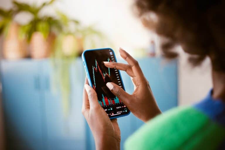 Mujer negra usando un teléfono inteligente en casa, mirando mapas de árboles.