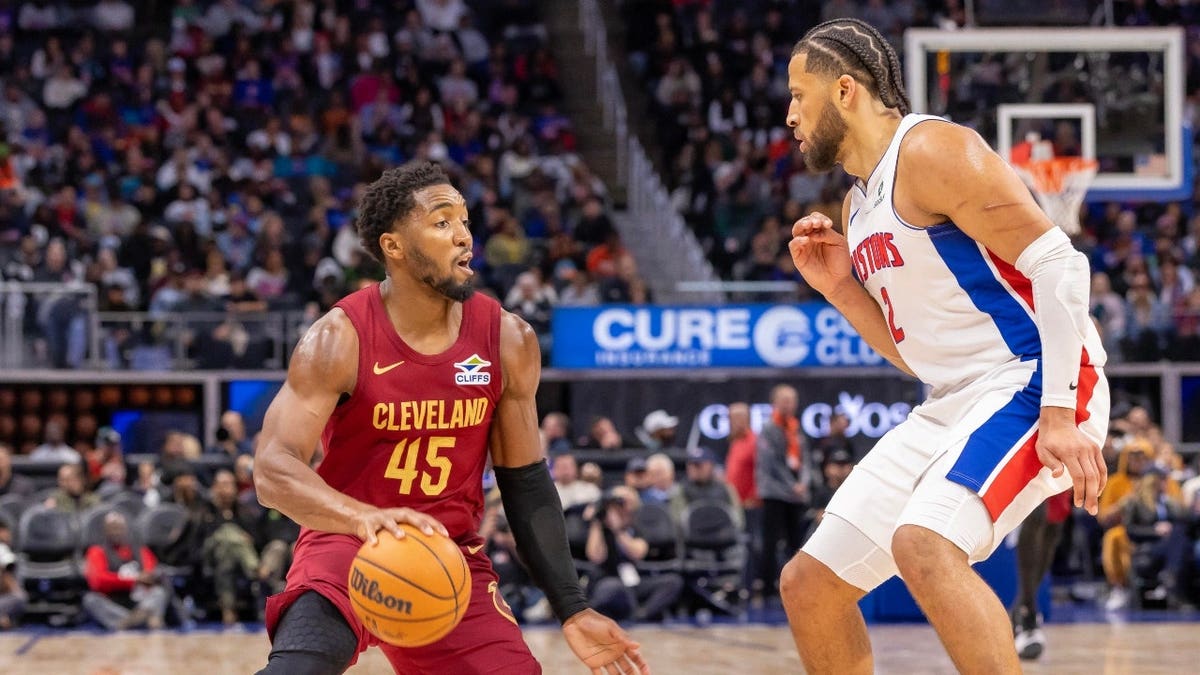 La acción estalló dentro del Little Caesars Arena en Detroit, Michigan, mostrando a Cade Cunningham de los Detroit Pistons defendiendo a Donovan Mitchell de los Cleveland Cavaliers durante un partido de baloncesto.